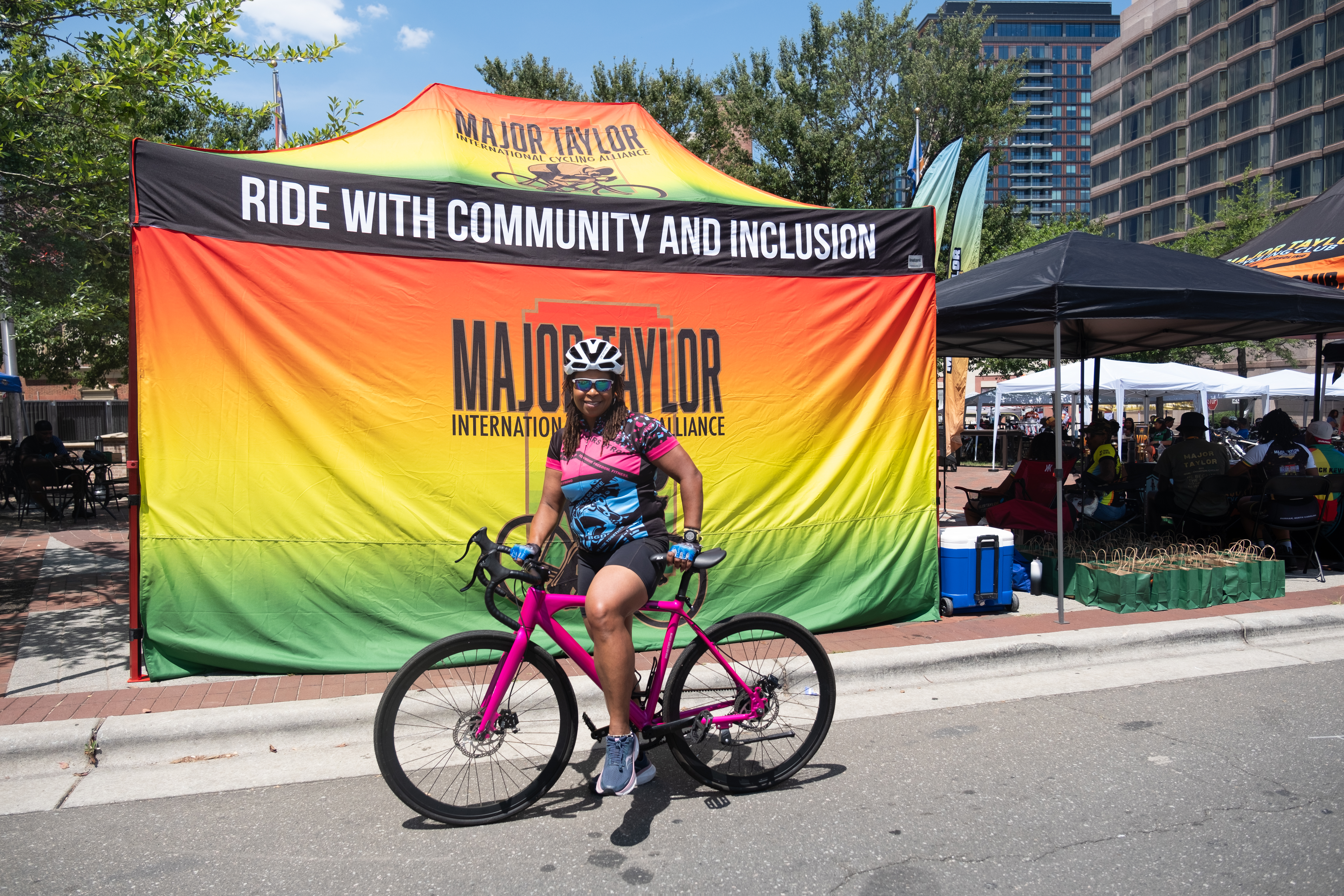 Cyclist with pink road bike posing at the Major Taylor International Cycling Alliance banner at Major Taylor Village in Durham NC