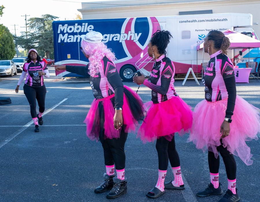 Major Miles for Mammograms riders beside a mobile mammography unit at a community screening event